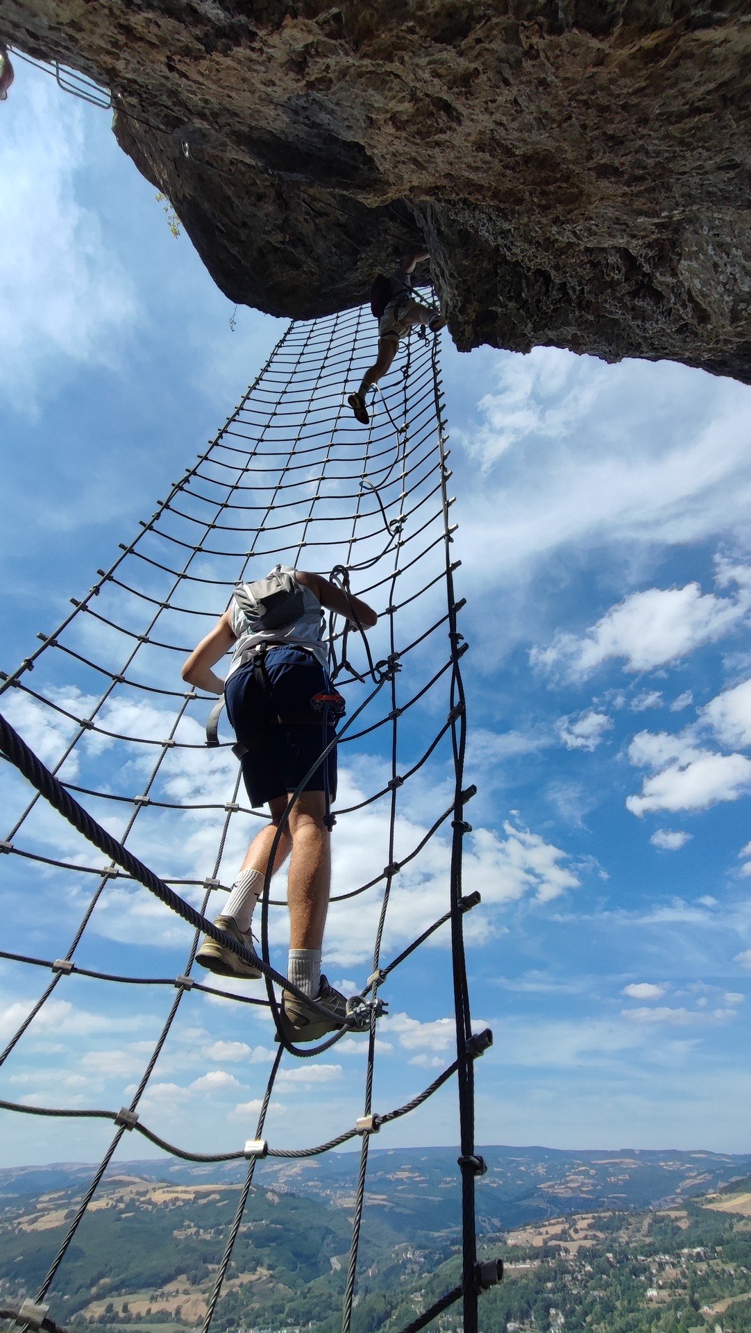 Participant dans le filet vertical sous un surplomb rocheux.